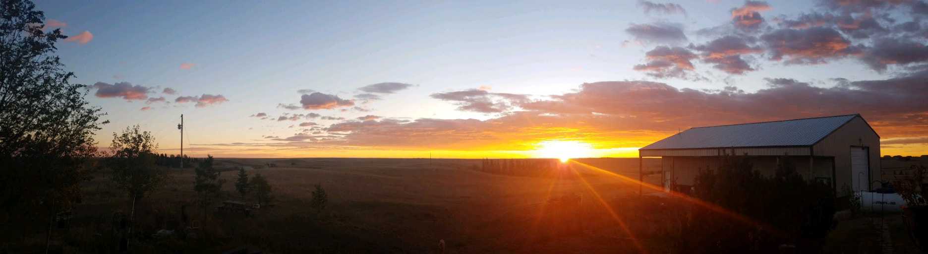 Sunset over open prairie beside the Realistic Illusions workshop building