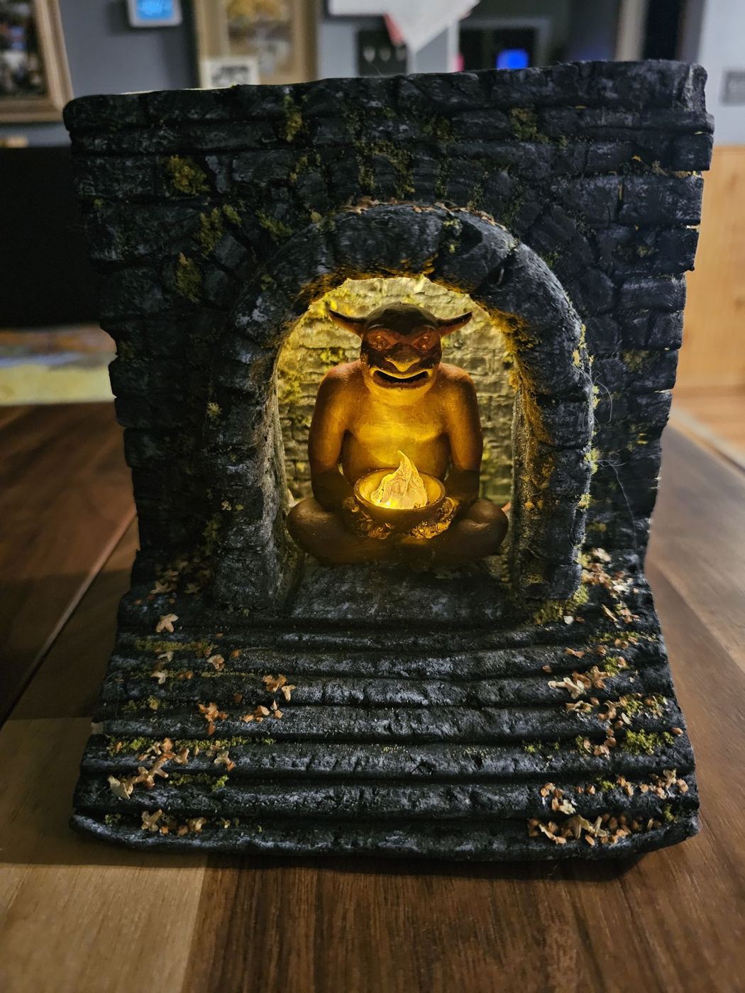 A glowing golden imp set into a dark sculpted stone archway